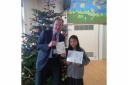 Makayla Garcia, from Trinity Primary School, shows off her winning design with Hereford and South Herefordshire MP Jesse Norman.