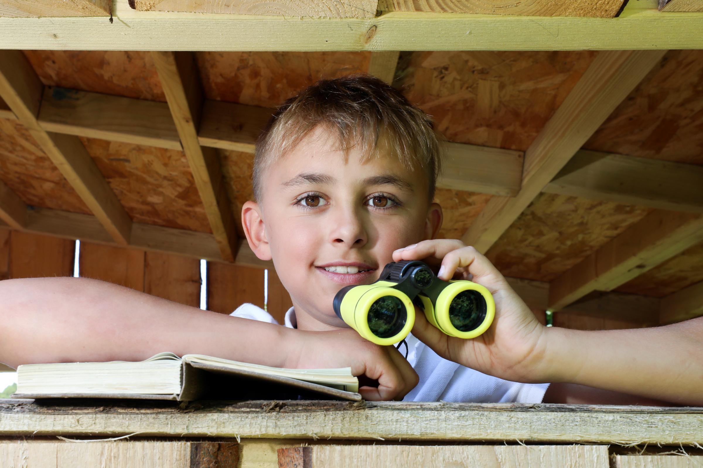 Isaac with his binoculars watches from the schools nature hut.