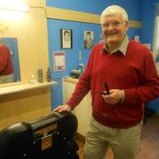 Colin where his customers will remember him - behind the chair in his barbershop